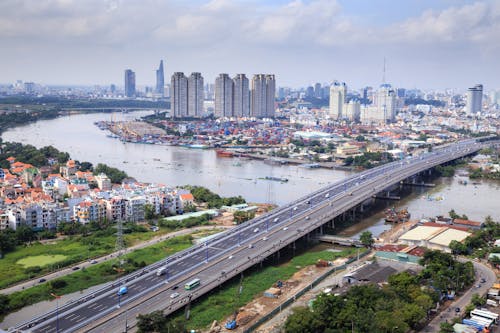 Free Different Vehicles on Road Near High-rise Buildings Showing Bridge and Sea Stock Photo