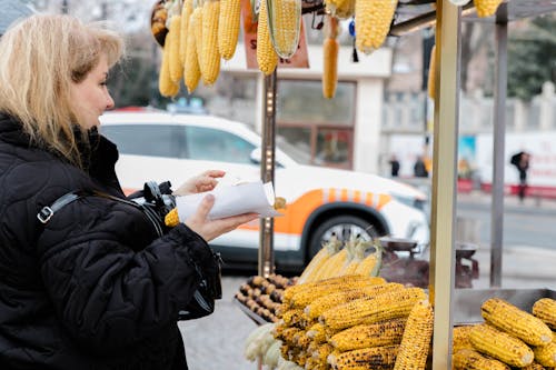 A woman is looking at corn on the street