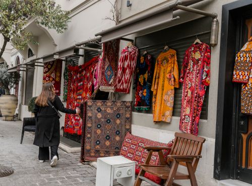 Free Woman browsing vibrant textiles on an urban street's sidewalk market. Stock Photo