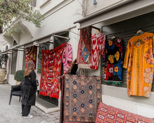 A woman is looking at some rugs on display