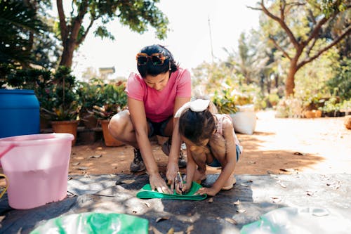 Free Woman Playing with Her Daughter While Working in the Garden Stock Photo