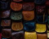 A vibrant collection of handcrafted Moroccan leather bags, showcasing unique patterns and designs.