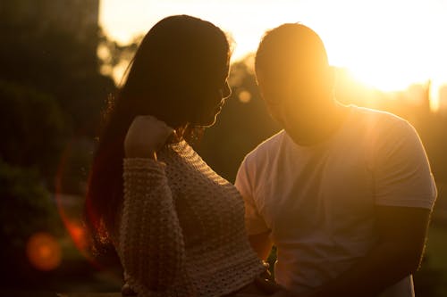A pregnant woman and her husband are standing in the sun