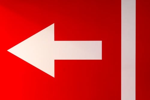 A red and white arrow sign with a white arrow