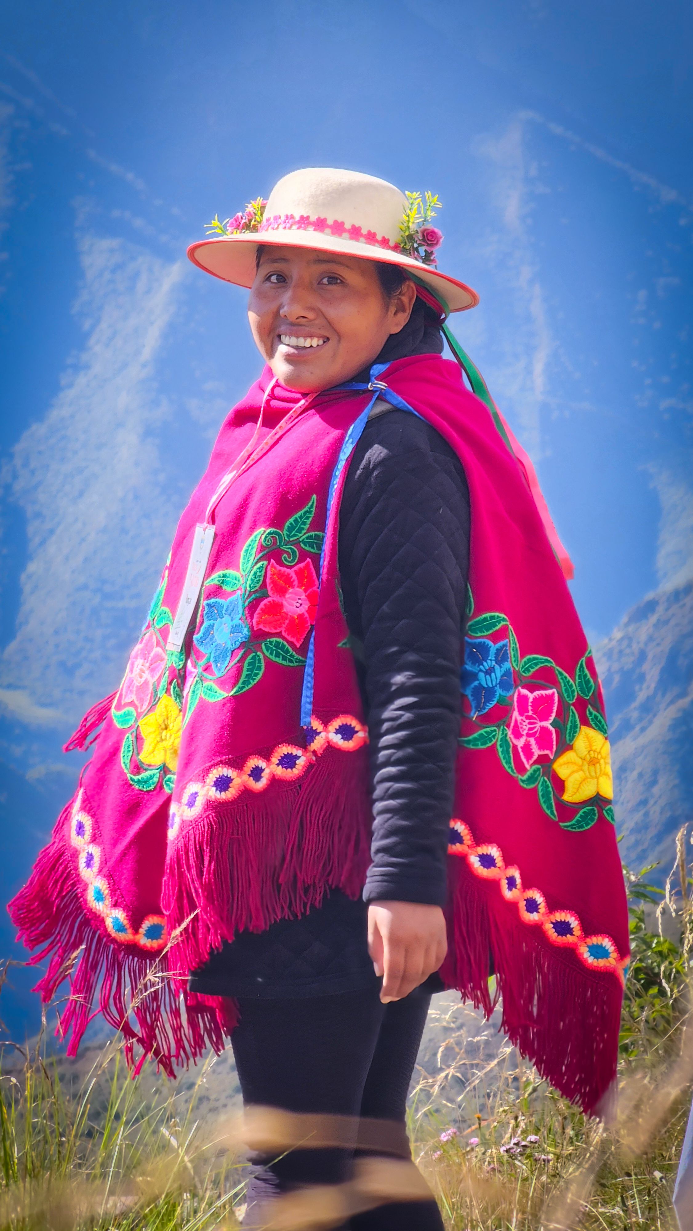 Woman in colorful poncho smiling in the scenic outdoors of Santa Ana, Jujuy, Argentina.