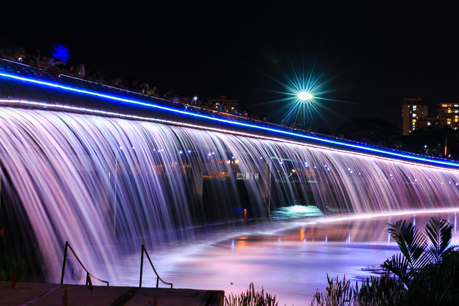 Beautifully lit waterfall bridge at night with long exposure effect.