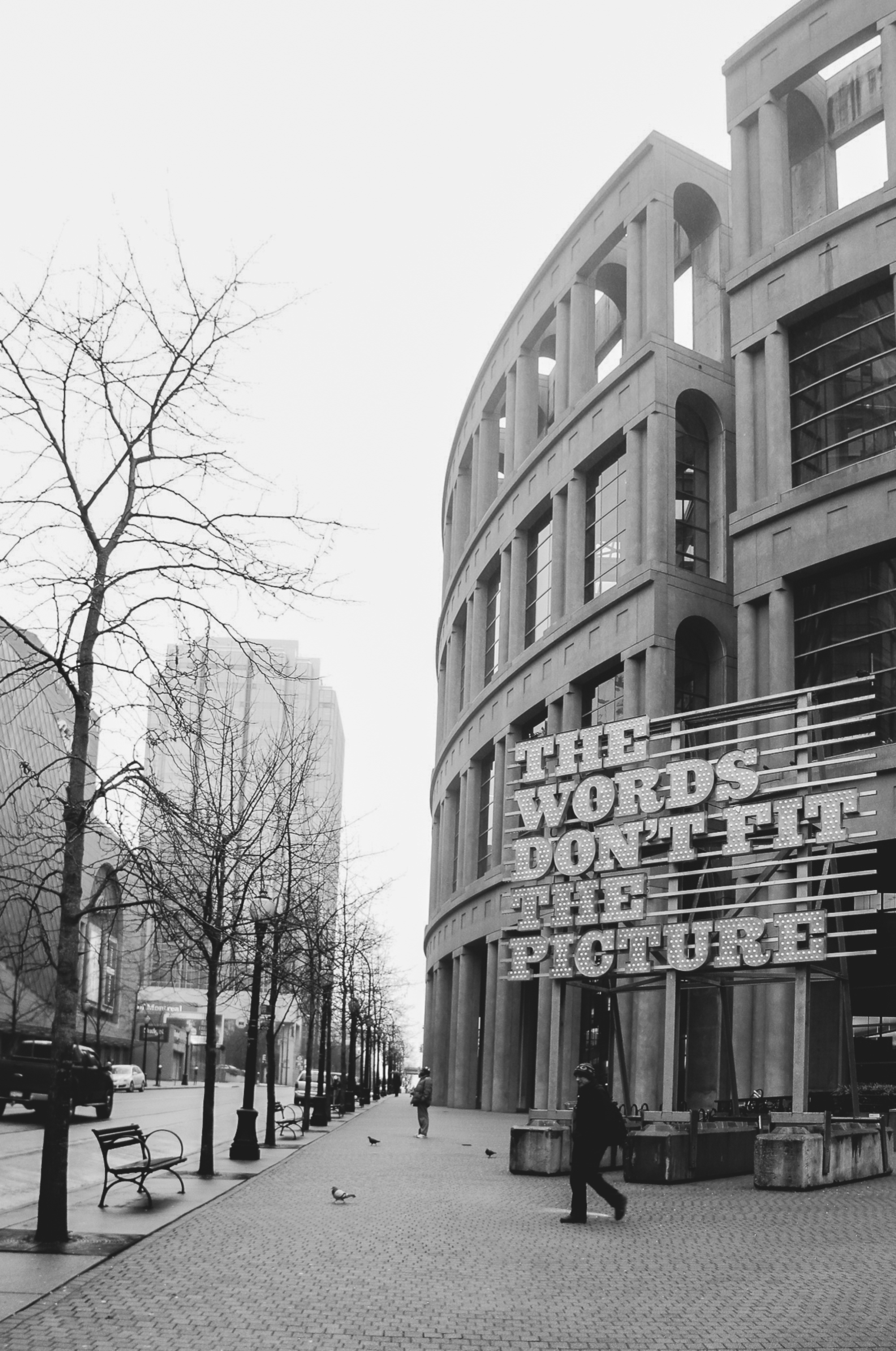 Black and white photo of Vancouver Public Library with urban street scene.