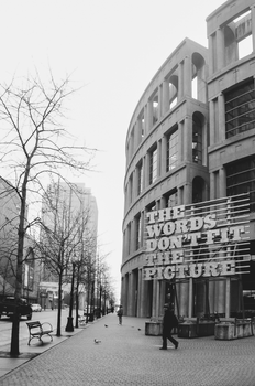 Black and white photo of Vancouver Public Library with urban street scene.