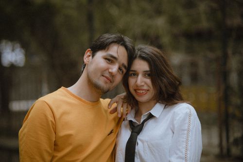 Free Charming couple posing outdoors in relaxed, casual clothing, displaying joyful expressions. Stock Photo