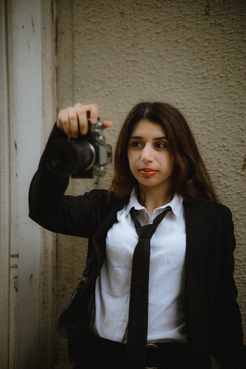 A woman in a suit holding a camera