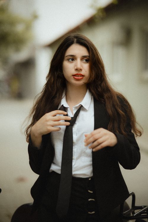 Free Chic urban portrait of a woman in a black jacket and tie, exuding confidence and style. Stock Photo