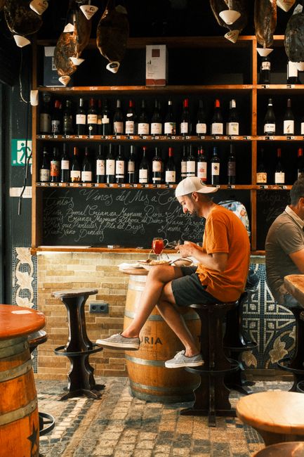 A relaxed scene of a man enjoying tapas and wine in a cozy Barcelona bar.