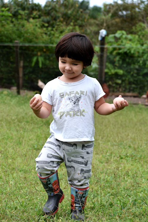 Free Boy in T-Shirt Holding Eggs in Hands Stock Photo