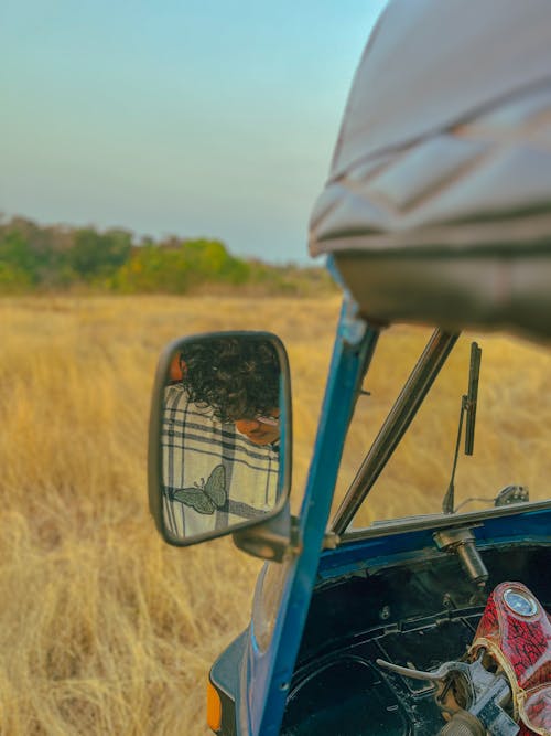 Man Reflection in Vehicle Mirror on Field