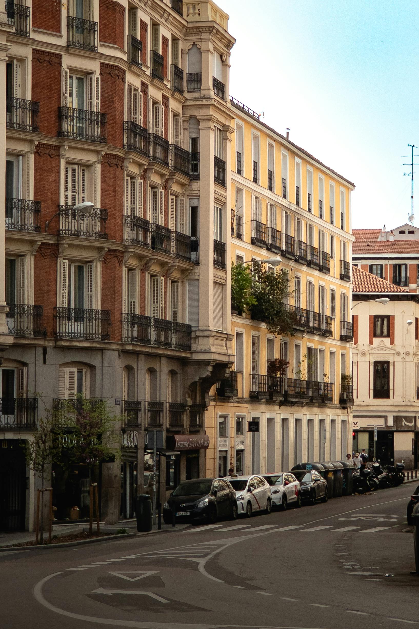 Elegant apartment buildings line a sunny street in Madrid. Urban residential area with classic architecture.