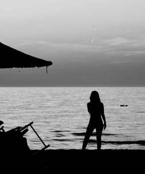 A woman's silhouette on a serene beach in Durrës, capturing a peaceful moment at sunset.