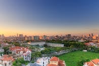 日落时分，鸟瞰图中展现出一座充满活力的城市景观，绿意葱茏，建筑林立