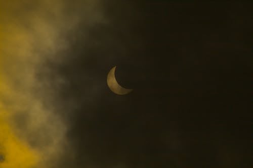 A partial eclipse of the sun seen through a cloudy sky