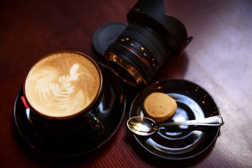 黑茶杯充滿咖啡在相機鏡頭旁邊