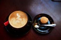 深色木桌上，精美的卡布奇诺咖啡与拿铁艺术，配着小饼干