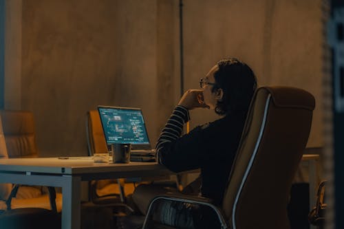 Free Candid Photo of a Man Sitting at a Table and Using a Laptop  Stock Photo