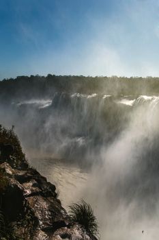 Breathtaking view of Iguazu Falls with mist and clear blue sky, a UNESCO World Heritage Site.