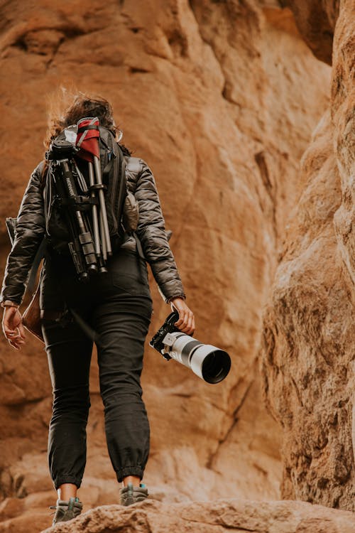 A woman with a camera and backpack on a rock