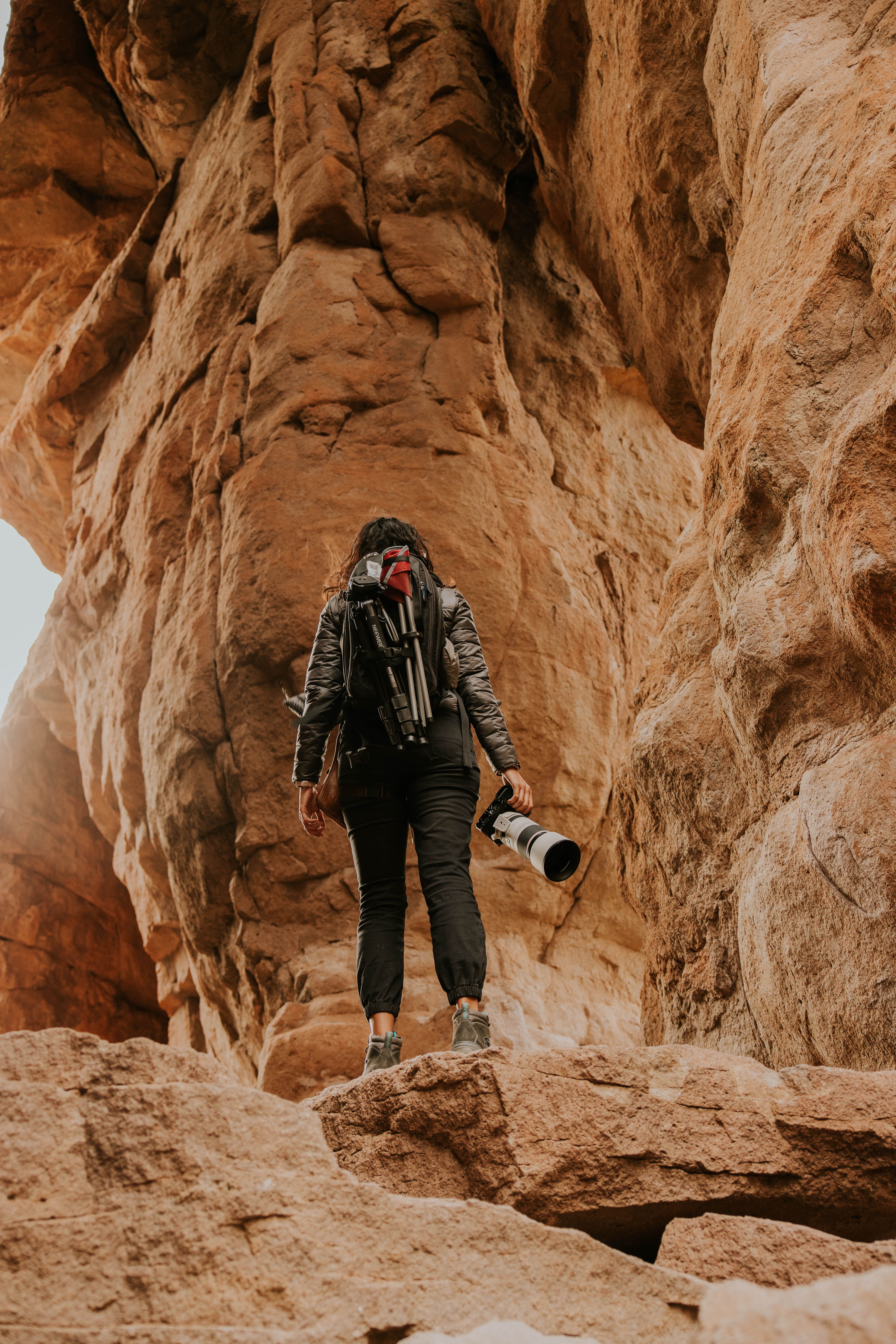 A female photographer explores a rugged canyon, capturing nature's beauty.