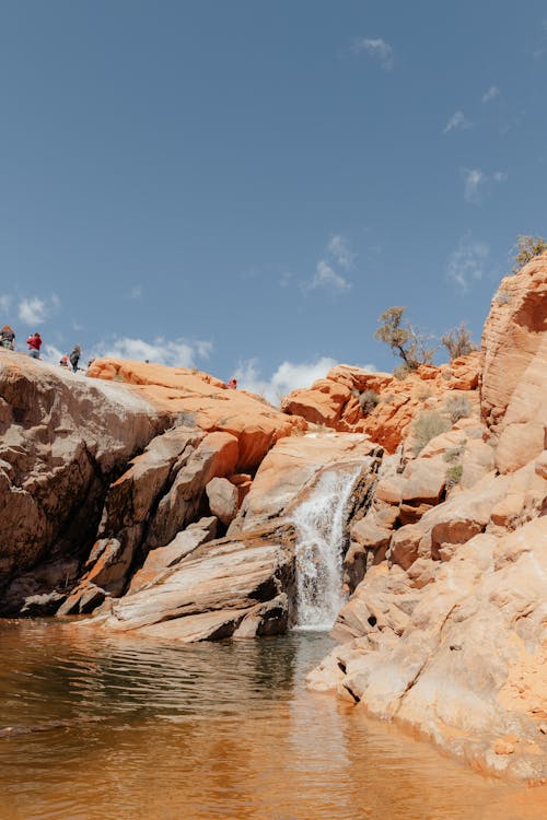 A waterfall in the desert with people standing around it