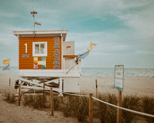 A lifeguard tower on the beach with a sign