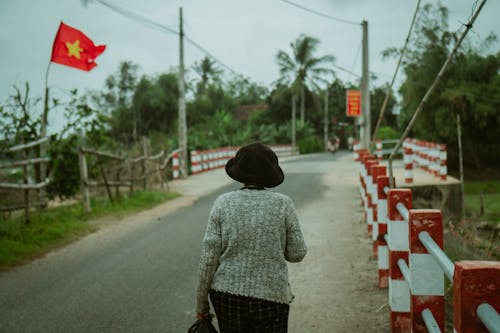 A woman walking down a road with a vietnamese flag