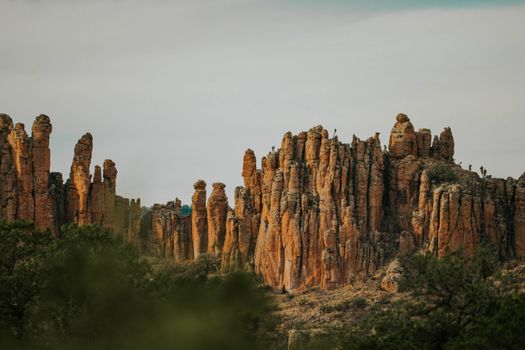Explore towering rock formations under a cloudy sky, capturing the desert's rugged beauty.