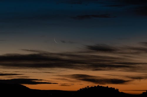The moon and crescent are seen in the sky at sunset