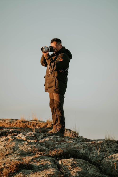 Man Holding a Camera in a Rocky Valley 