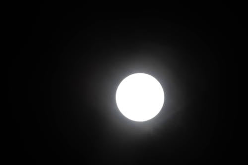 A full moon is seen in the dark sky