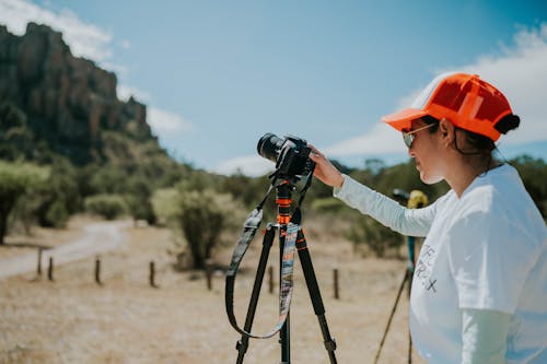 A woman in an orange hat is taking pictures with a camera