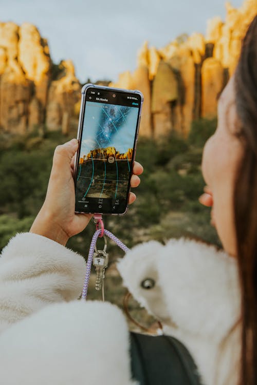 A woman taking a picture of a mountain with her phone