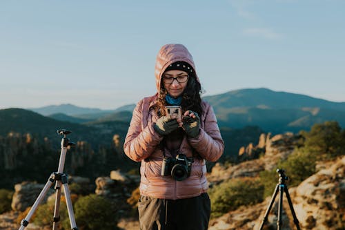 A woman taking a photo with her phone while standing on a mountain