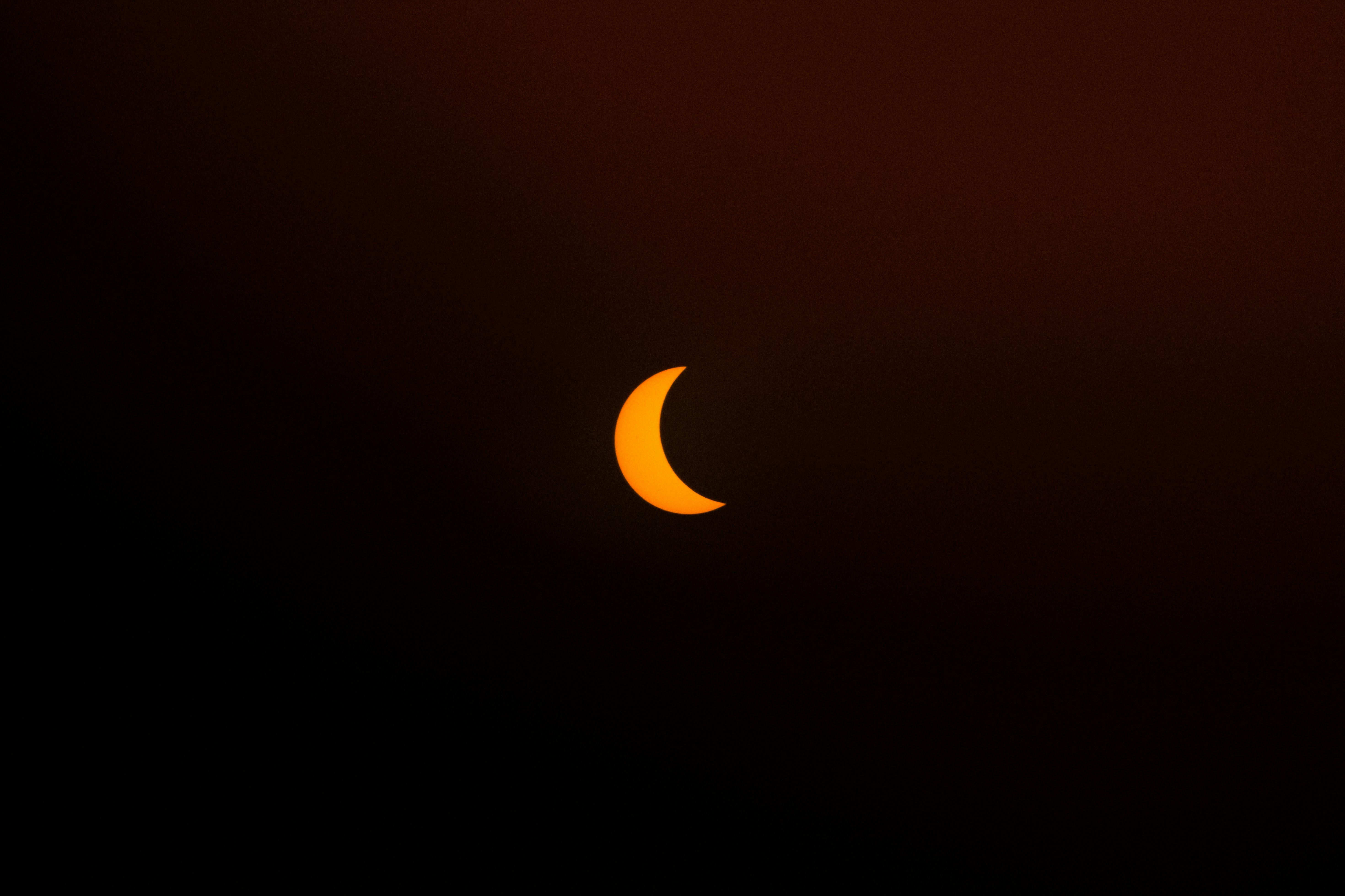 A stunning crescent moon set against a dark orange sky, perfect for night sky enthusiasts.