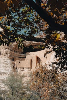 Explore the historical cliff dwellings nestled in Arizona's rugged landscape with autumn foliage.