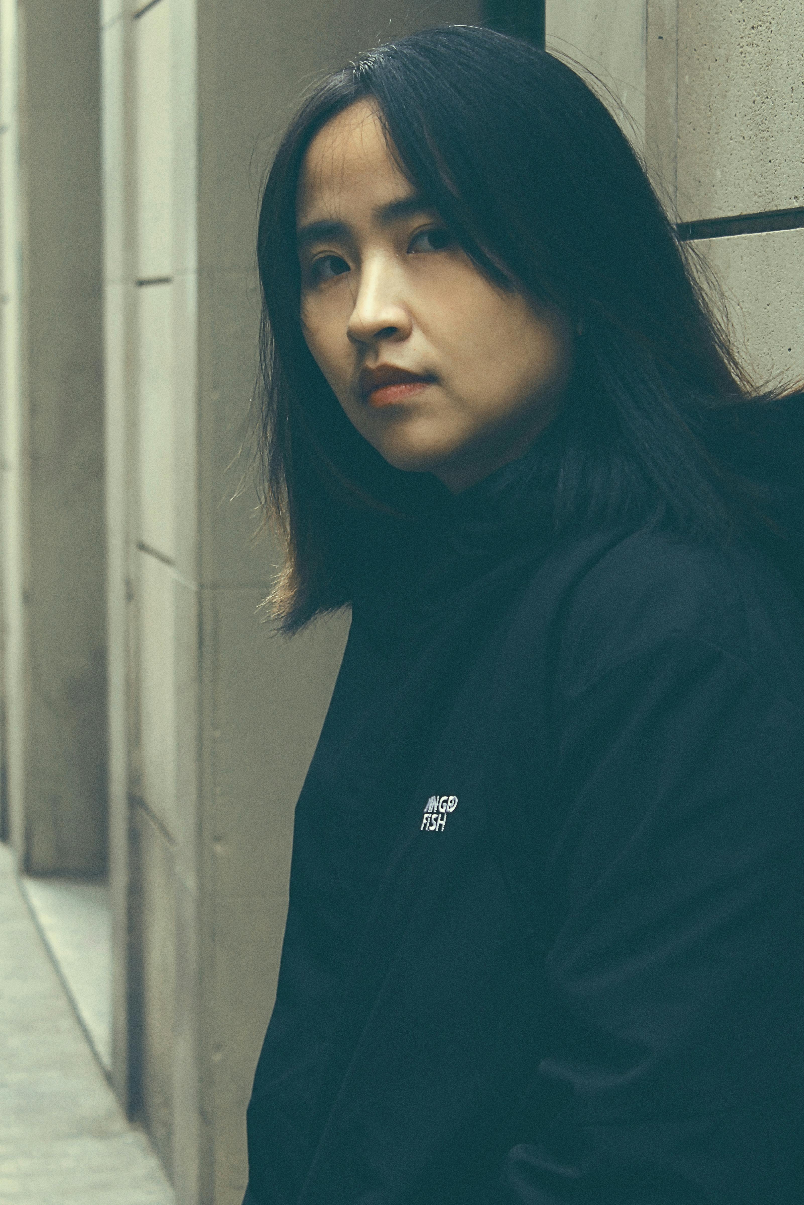 Moody portrait of a woman in an urban setting, showcasing modern fashion.