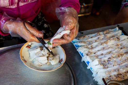 Close-up of hands crafting Vietnamese rice paper rolls with gloves.