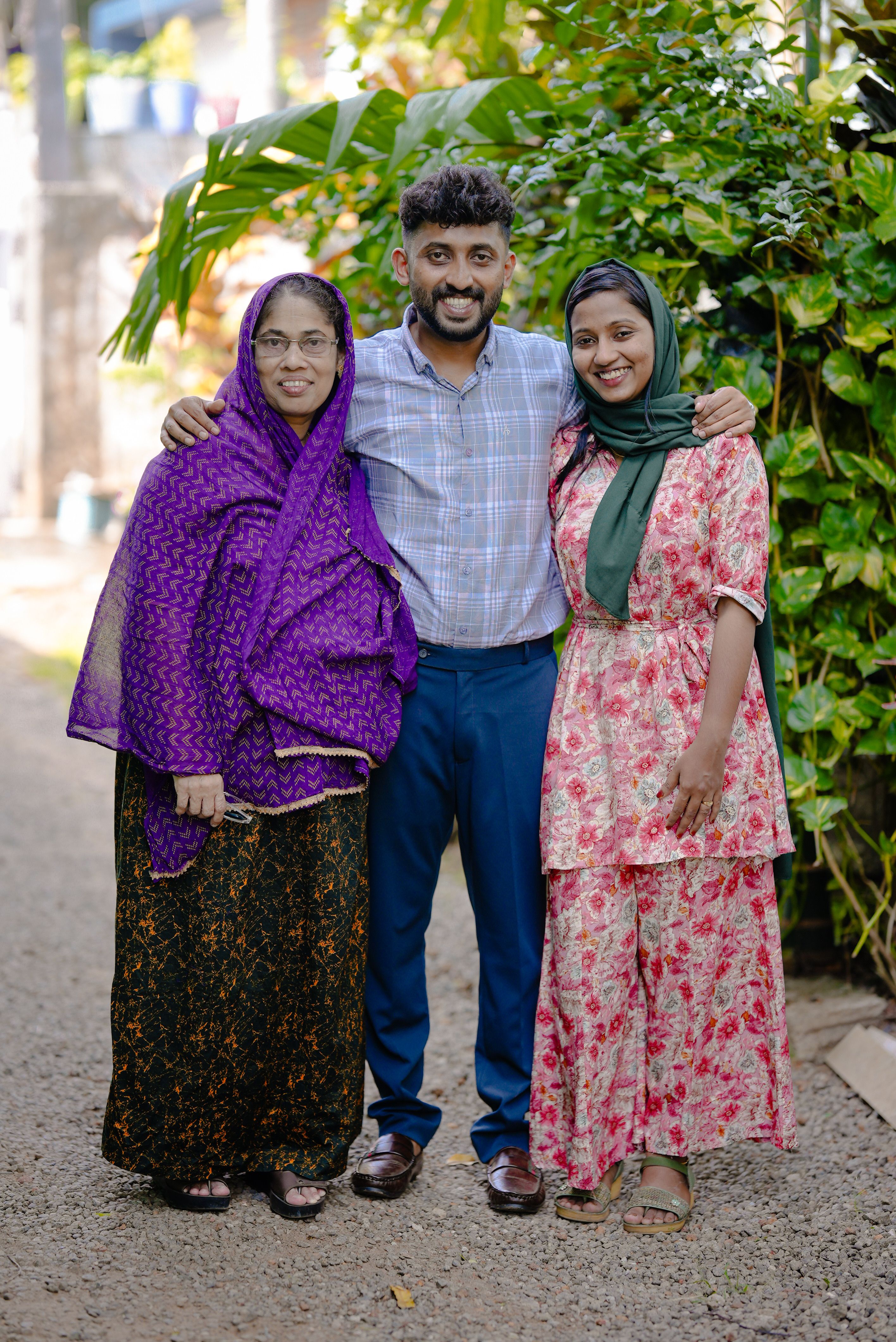 Smiling family embracing outdoors in traditional clothing on a sunny day.