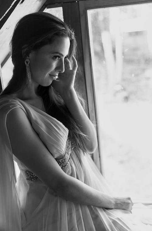 Free A woman in a white dress sitting by a window Stock Photo