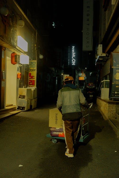 A man pushing a cart down a dark alley