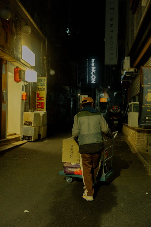 Free A man pushing a cart down a dark alley Stock Photo