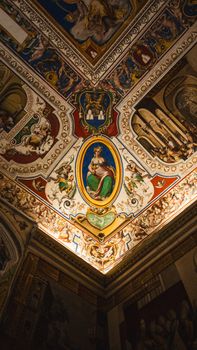 Intricately decorated ceiling in a historic palace featuring classic frescoes and ornate designs.