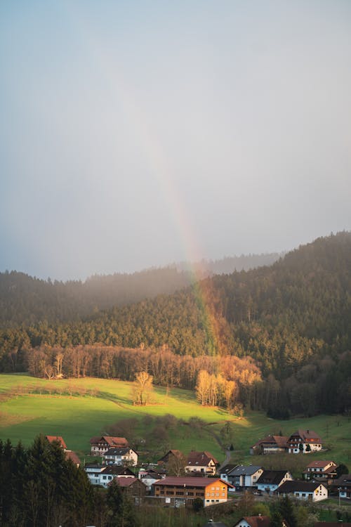A rainbow appears over a small village in the mountains
