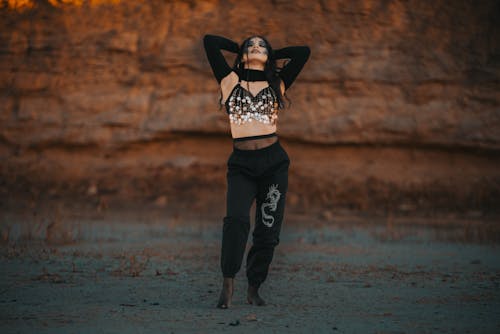 Free A woman in a crop top and pants standing on a rock Stock Photo