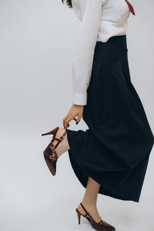 A woman in a skirt and heels is holding her hand